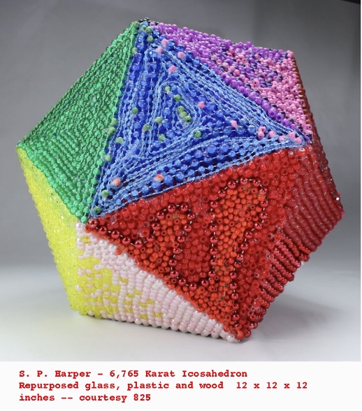 A three-dimensional art sculpture of a multi-colored, beaded object in the shape of a hexagon. 